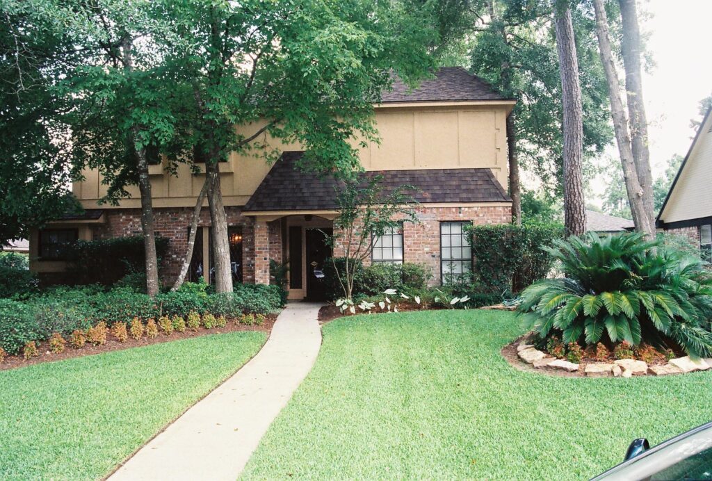 Daytime photo of home with well-manicured lawn and sago palm