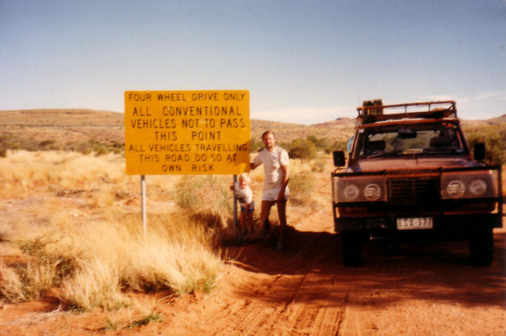 Eric and Glenn Robinson stand beside a 4x4 road sign in rural Australia