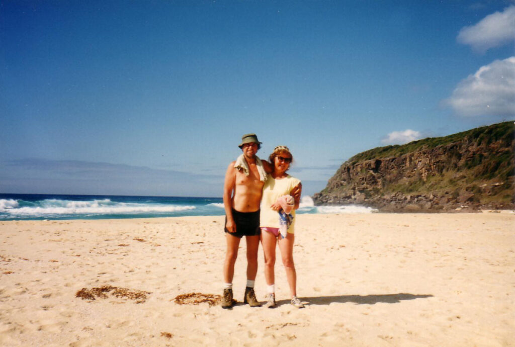 Eric and Helen Robinson stand on a sunny beach