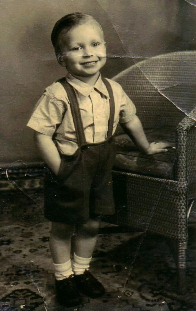 A young boy, Eric Robinson, smiles next to a wicker chair
