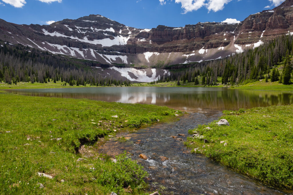 A small mountain lake, or tarn, sits below a triangular peak