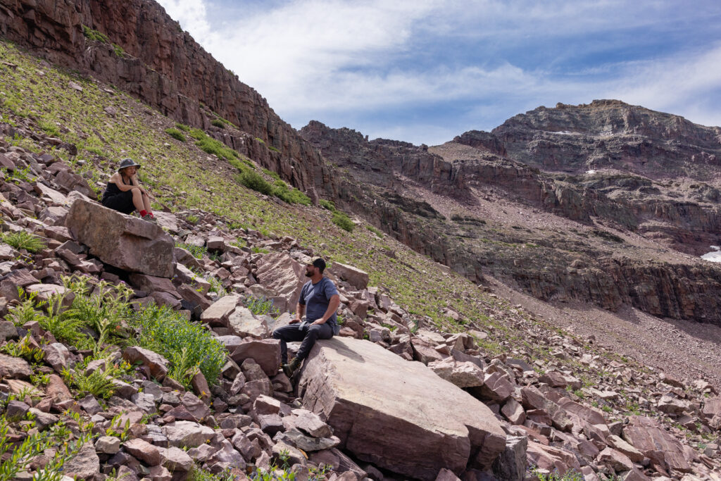 Marilyn Koolstra and Kelvin Judd sit on rocks on a steep mountain slope
