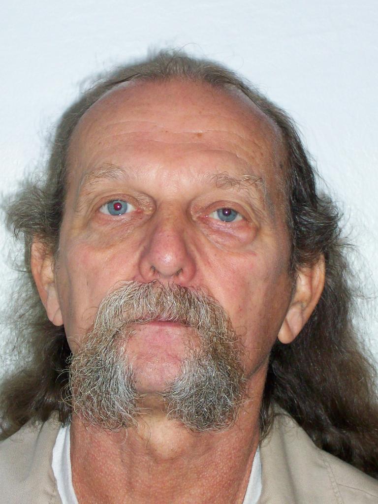 A police photo of a man with long hair and a gray mustache.